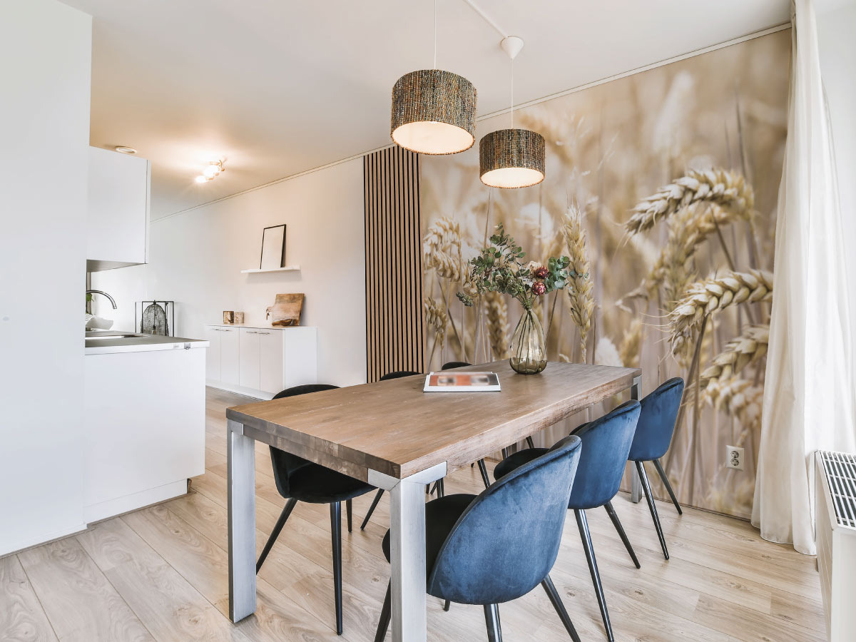 Salle à manger avec un papier peint panoramique champs de blé, des tasseaux de bois et des chaises bleues